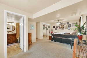 Bedroom with light colored carpet and connected bathroom