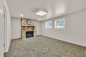 Unfurnished living room with a fireplace, carpet floors, a textured ceiling, recessed lighting, and baseboards