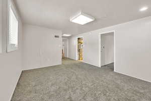 Unfurnished room with carpet, baseboards, and a textured ceiling