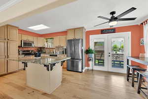 Kitchen featuring appliances with stainless steel finishes, crown molding, tasteful backsplash, light stone countertops, and a ceiling fan