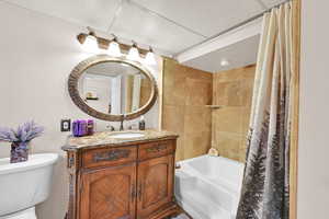 Bathroom with toilet, vanity, and shower / bath combo with shower curtain