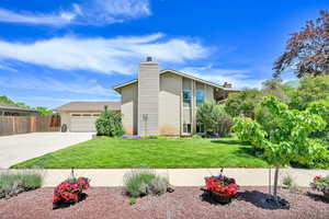View of front of home featuring concrete driveway, an attached garage, and a chimney