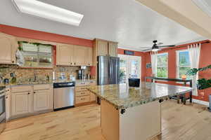 Kitchen featuring stainless steel appliances, light wood finished floors, backsplash, a kitchen island, and a textured ceiling