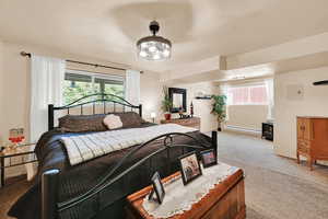 Carpeted bedroom featuring a baseboard heating unit, multiple windows, a textured ceiling, and baseboards
