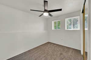 Carpeted empty room featuring ceiling fan, baseboards, and a textured ceiling