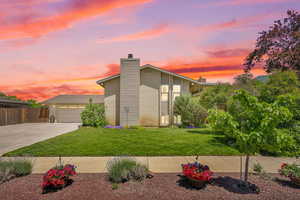 Mid-century inspired home with concrete driveway, a chimney, and brick siding