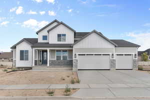 View of front facade featuring covered porch, board and batten siding, an attached garage, driveway, and stone siding