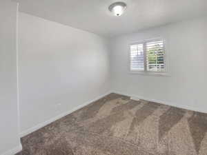 Empty room featuring carpet and baseboards