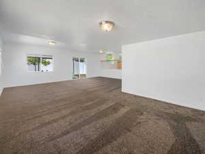 Empty room with carpet floors and a textured ceiling