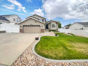View of front facade with a gate, brick siding, concrete driveway, and an attached garage