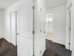 Corridor with dark carpet and baseboards