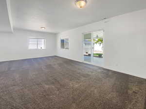 Unfurnished room with dark carpet and baseboards