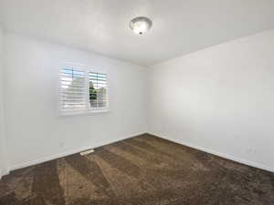 Empty room with dark carpet and baseboards