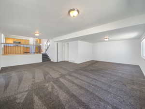 Finished below grade area featuring stairs, carpet floors, and baseboards