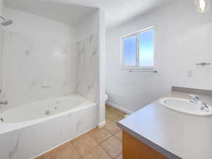 Full bath with vanity, toilet, tile patterned floors, a combined bath / shower with marble appearance, and baseboards
