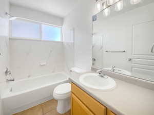 Bathroom featuring vanity, toilet, tile patterned floors, and shower / washtub combination