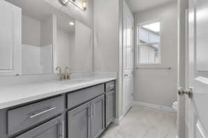 Bathroom featuring marble finish floors, vanity, toilet, baseboards, and recessed lighting