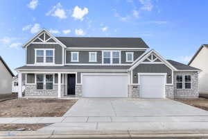 Craftsman inspired home with board and batten siding, stone siding, driveway, and a porch