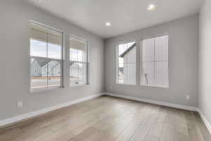 Unfurnished room with healthy amount of natural light, baseboards, recessed lighting, and light wood-style floors