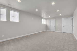 Spare room featuring recessed lighting, light colored carpet, and baseboards