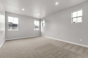 Unfurnished room featuring light carpet, baseboards, and recessed lighting