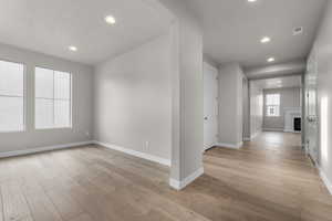 Unfurnished room featuring baseboards, light wood finished floors, recessed lighting, and a fireplace