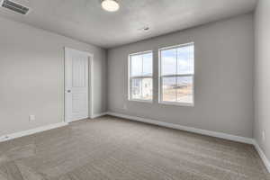 Unfurnished room with a textured ceiling, carpet flooring, and baseboards