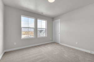 Unfurnished room featuring a textured ceiling, light colored carpet, and baseboards