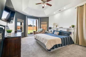 Carpeted bedroom with access to outside, a raised ceiling, recessed lighting, and ceiling fan