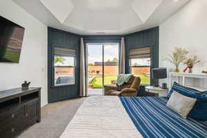 Bedroom featuring a tray ceiling, access to outside, and light colored carpet
