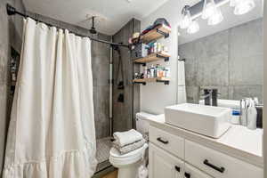 Full bathroom with toilet, a tile shower, and vanity