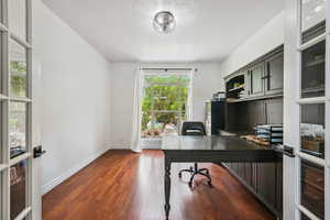 Office space featuring dark wood-style flooring, a textured ceiling, and baseboards