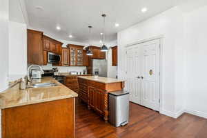 Kitchen featuring stainless steel appliances, a sink, dark wood-style floors, light stone counters, and recessed lighting