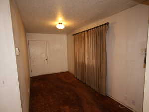 Corridor with a textured ceiling and dark carpet