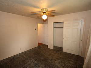 Unfurnished bedroom featuring carpet, a textured ceiling, a closet, and a ceiling fan