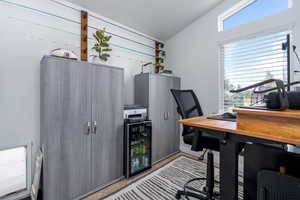 Home office featuring wine cooler and lofted ceiling
