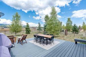 Wooden terrace featuring outdoor dining area, a fenced backyard, and a view of countryside