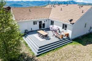 Rear view of house featuring stucco siding, a deck with mountain view, a shingled roof, and outdoor dining area