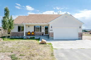 Single story home with brick siding, an attached garage, covered porch, and concrete driveway