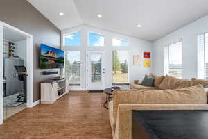Living room with lofted ceiling, wood finished floors, plenty of natural light, recessed lighting, and baseboards