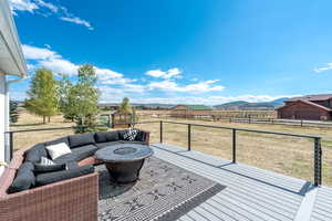 Deck with an outdoor living space with a fire pit, a mountain view, a view of rural / pastoral area, and an outdoor structure