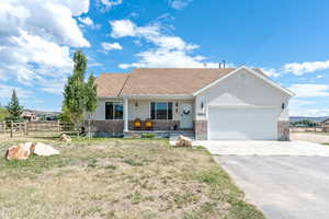 Single story home with a porch, brick siding, an attached garage, and driveway