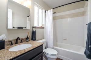 Bathroom with toilet, shower / bath combo, and vanity