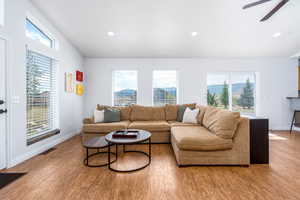Living area featuring light wood-style floors, ceiling fan, baseboards, and recessed lighting
