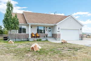 Single story home featuring brick siding, covered porch, an attached garage, concrete driveway, and roof with shingles