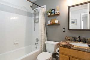 Full bath featuring shower / bath combination with curtain, toilet, and vanity