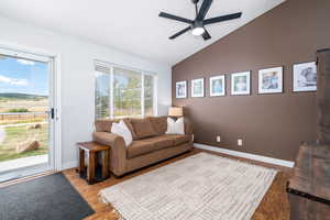 Living room featuring lofted ceiling, a ceiling fan, wood finished floors, and baseboards