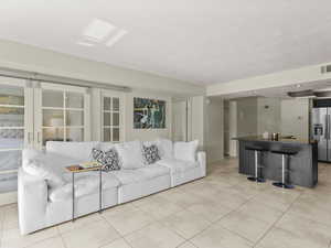 Living room featuring light tile patterned floors, baseboards, and a textured ceiling