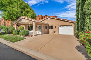 View of front of property featuring covered porch, a garage, stucco siding, a tiled roof, and driveway