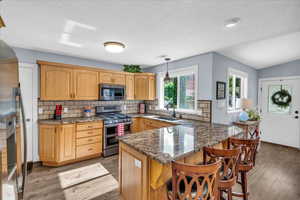 Kitchen with stainless steel appliances, a sink, light wood-type flooring, a peninsula, and backsplash